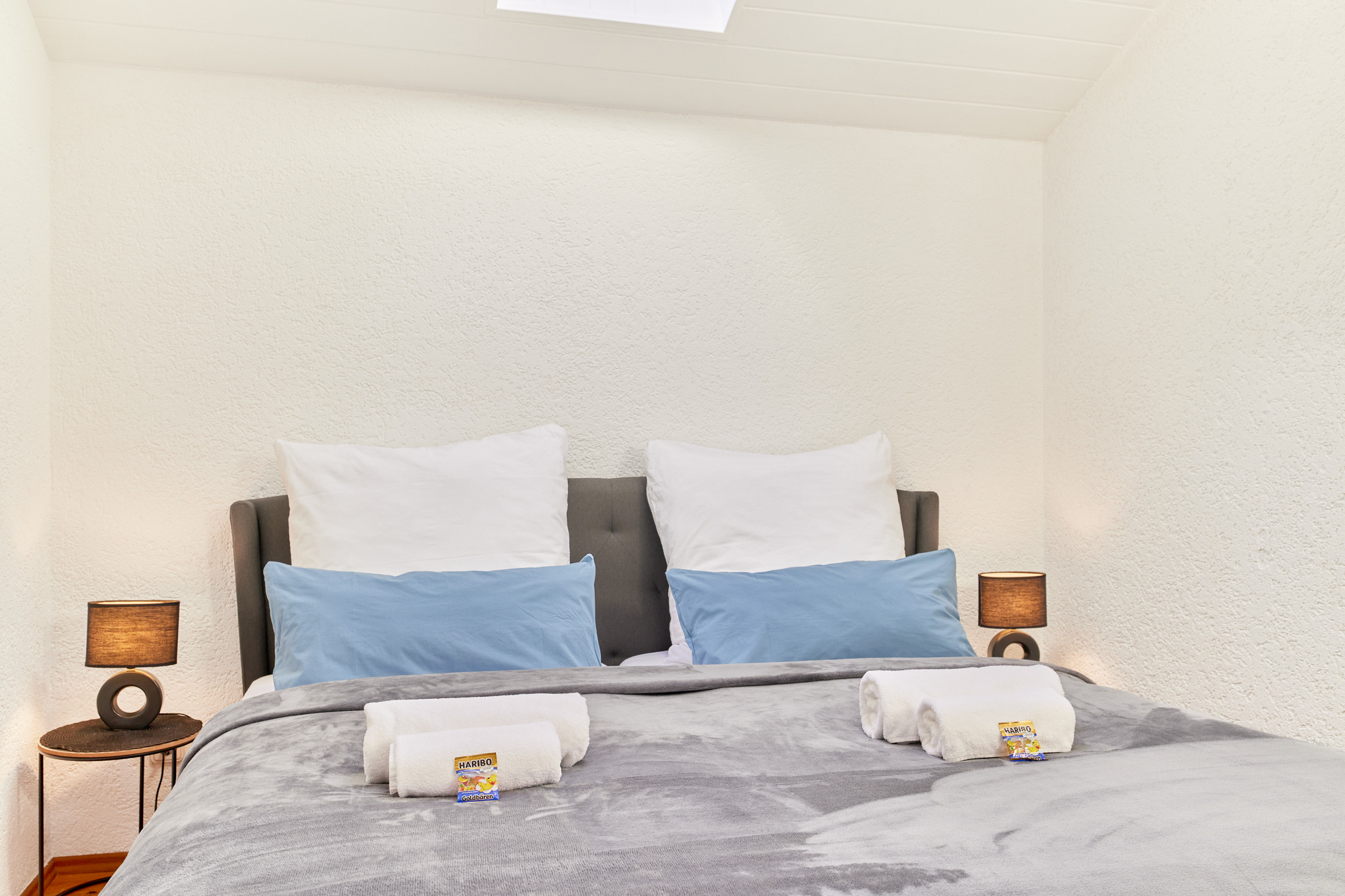 frisch bezogenes Doppelbett mit kissen und frischen handtüchern im schlafzimmer der traumferienwohnung domblick 1