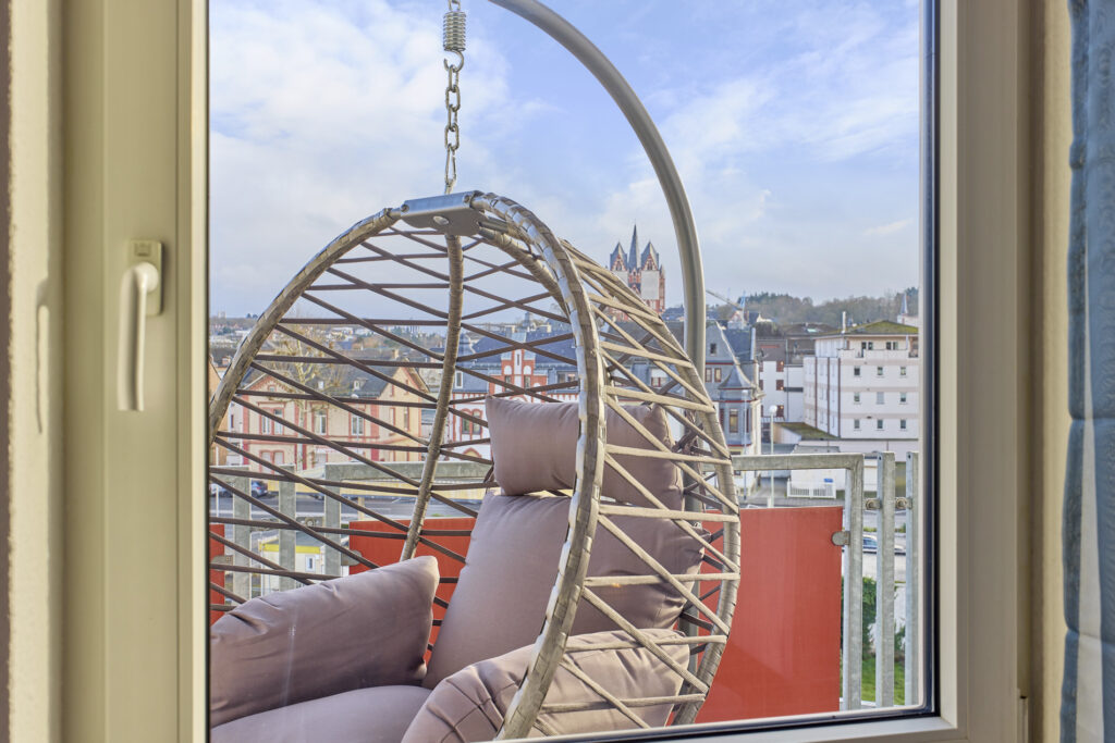Balkon mit Domblick – Entspannen im Hängesessel oder bei einem Essen im Freien
Der möblierte Balkon unserer Ferienwohnung in Limburg bietet einen traumhaften Blick auf den Dom. Ein bequemer Hängesessel und eine stilvolle Essgarnitur laden dazu ein, den Ausblick in vollen Zügen zu genießen.